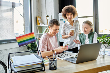Joyous diverse businesswomen, including members of the LGBT community, working intently around a...