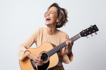 Portrait of a joyful woman in her 40s playing the guitar in white background