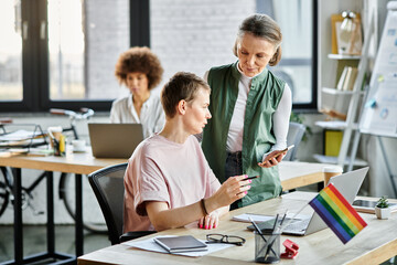Fototapeta premium Appealing diverse businesswomen working together on project in office, pride flag.