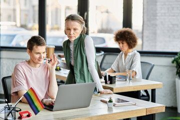 Attentive diverse businesswomen working together on project in office, pride flag.
