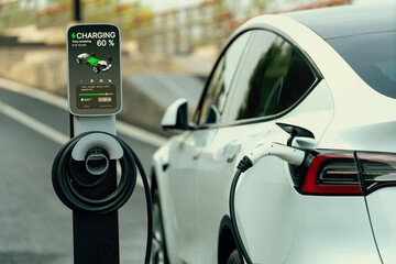 Electric car recharging battery at outdoor EV charging station for road trip or car traveling,...
