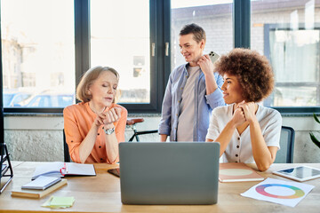 Multicultural group of businesswomen collaborating around a table with a laptop in an office setting.