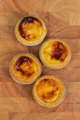 Freshly baked homemade egg tarts on a wooden background.