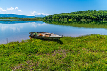 A view past a boat on the shoreline of a lake at Belsh lakes in Albasan county, Albania in...
