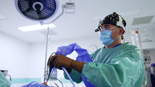 Operating otolaryngologist holding tools in the nose of patient. Low angle view on the doctor performing surgery.