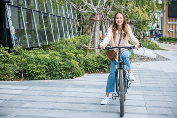 Happy Asian beautiful young woman riding bicycle on street outdoor near building city, Portrait of...