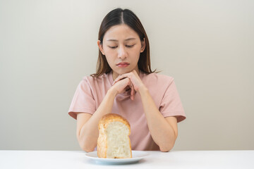 Gluten allergy asian young woman expression face, looking bread refusing to eat on plate in...