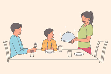 Caring woman serves dinner to husband and son sitting at table, during family holiday