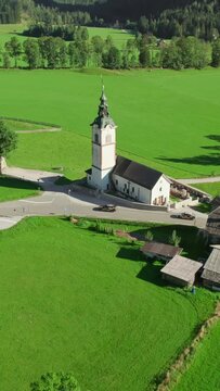 Traditional Slovenian Church of St. Andrei in Ravenska Kocna valley with the Kamnik-Savinja Alps in the background. An aerial summer view of the idyllic Alpine landscape in Zgornje Jezersko, Slovenia