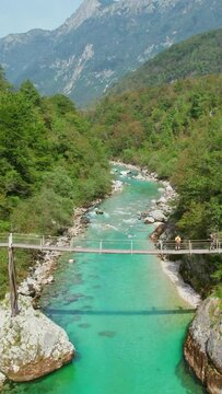 A suspension bridge over emerald waters of the Soca River, Slovenia, aerial view. Soca river canyon is a favoured destination for kayaking and trekking in Slovenia. Kayakers on Soca river in Slovenia
