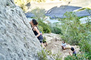 Multiple climbers scaling a steep rock wall in the mountains with a focus on their ascent