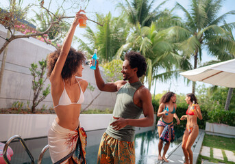 People having fun in a tropical pool house. Man and woman dancing, smiling, having fun.