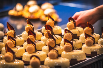 Hand of a bakery saleswoman puts glazed tarts on the sales counter. Preparation in the early morning for sales.