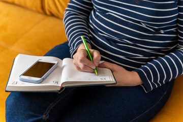  woman makes notes in a notebook while working with a smartphone