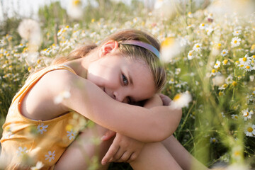 Child girl  sits in a meadow with a  of daisies in summer. Earth Day. World Environment Day. world...