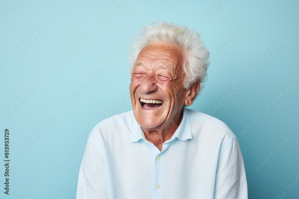 Wall mural portrait of a grinning man in his 70s laughing isolated on pastel blue background - Wall murals