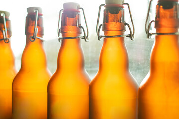 Brown beer bottles with bugle plug stand in a row by the window