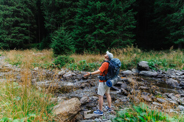 Hiker standing on stones by stream in mountains