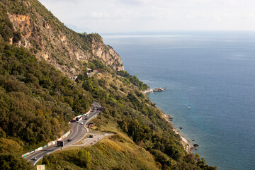 Blue sea and green mountains against the blue sky. Serpentine mountain road. Budva. A sailboat and a yacht on the Adriatic Sea. Spring and summer in Montenegro. Photo in high quality