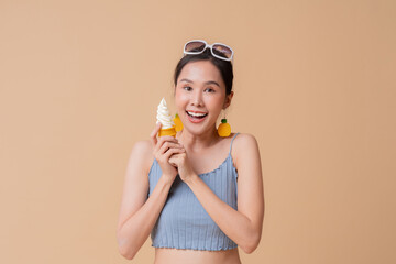 summer freshness asian cheerful swimwear woman wear sun glasses hand hold ice cream sweet dessert smiling happiness summertime advertisment studio photoshoot cute and curious friendly on color screen
