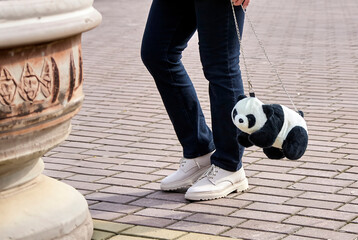 Stylish Woman with Adorable Panda Bag Strutting in Urban Setting, Trendy Street Fashion Scene
