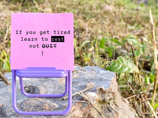 Inspirational motivational quote - IF YOU GET TIRED, LEARN TO REST, NOT QUIT. Note on paper with nature background. Stock photo