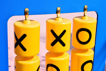 Close-up yellow plastic educational alphabet x and o black letters called tic-tac-toe game or XO board game at playgroup outdoor.