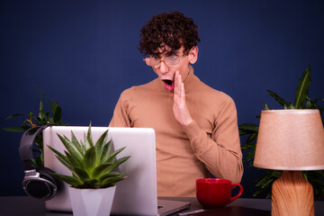 A young funny attractive guy studies, works and meets people online at home.