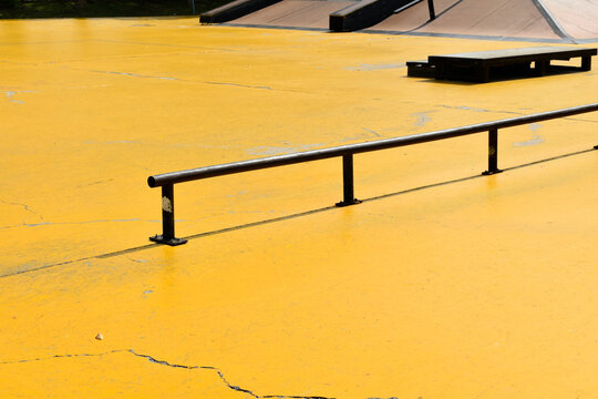 Black skateboard steel rail on a yellow concrete background is an area for skateboarding at an outdoor park. - Powered by Adobe