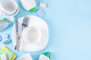 Dishwasher tablet for dish washing, detergents and accessories with plates, cups and cutlery on light blue background copy space 