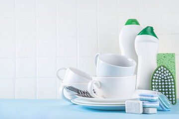 Dishwasher tablet for dish washing, detergents and accessories with plates, cups and cutlery on light blue background copy space 