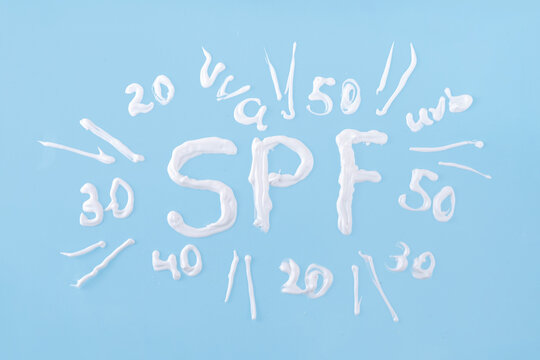 Choosing level degree of sun protection for adults or children. Plastic bottle of sunscreen lotion with cream text numbers of SPF, UVB, UVA filters, on bright background, top view flatlay copy space