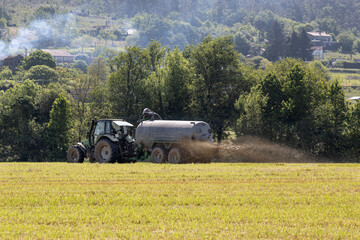 Scene of a tractor in a crop field spreading liquid manure