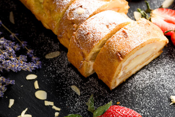 Sliced rolls with custard. The dessert is decorated with fresh strawberries