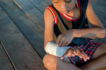 Close-up boy bandaging a wound on his arm with gauze caused by an accident for first aid and medical concept.