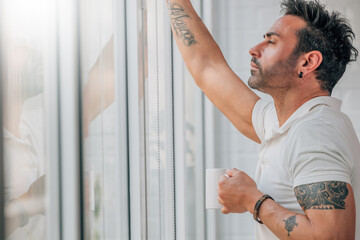 attractive man with beard drinking coffee at the window