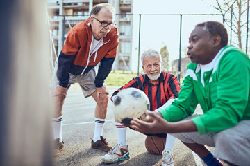 Senior soccer team taking a break and strategizing during game on urban court