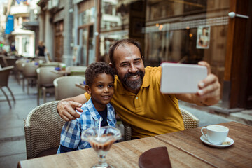 Father and son taking selfie at outdoor cafe