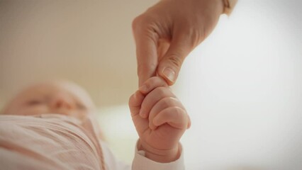 A newborn baby squeezes his mother's finger. Mom lovingly holds her baby's hand, feeling tenderness and care. Showing love and care. The gentle touch of a child's hand - Powered by Adobe