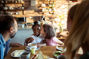 Young mixed family eating together at home