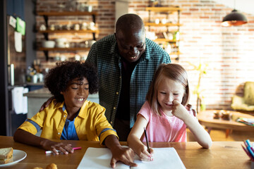 Father helping children with homework at kitchen table