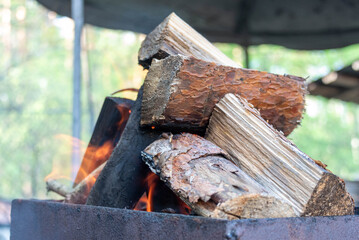 A pile of wood is burning in the brazier to make coals.