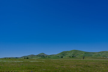 Green mountain tops under a blue sky.