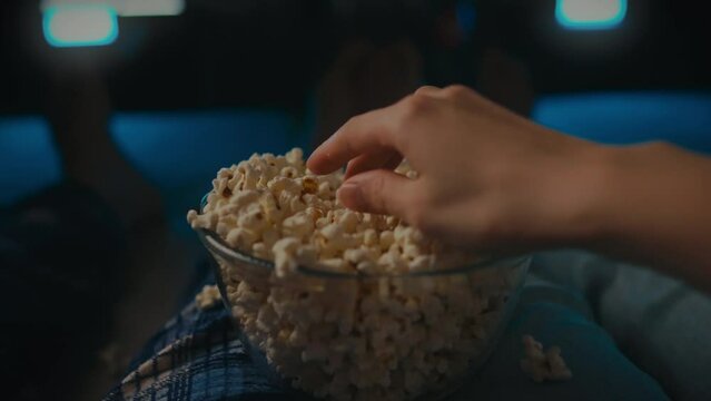 An evening movie session at home with a huge bowl of flavored popcorn in the hands of a young family. Husband, wife in front of the screen, enjoying these moments together