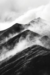 Image is black and white photo of mountain range with foggy clouds