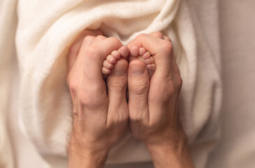 Baby feet of a newborn in dad's hands. On a white background.