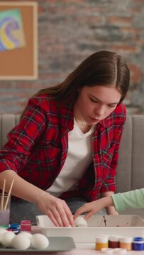 Pretty concentrated sisters color eggs with Ebru decor technique in living room slow motion. Easter holiday decoration ideas and traditions