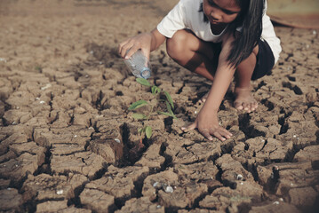 Asian girl planting tree and watering seedling on dry and crack ground to restore and change earth...