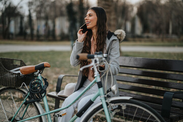 A professional female taking a relaxing break on a bench with her bicycle in the serene setting of a city park.