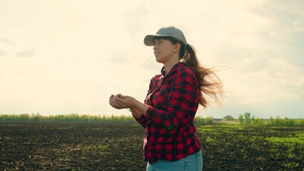 Woman agronomist checks quality of sowing grain. Business woman checks her field. Farmer checks...